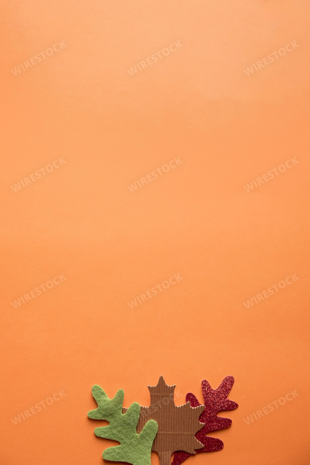 A vertical shot of an orange surface with cut out leaves in the bottom great for background or writing text
