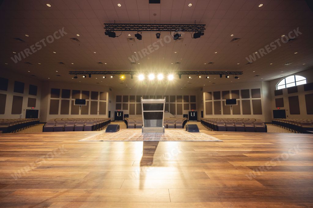 An illuminated empty hall with a stage and empty seats.