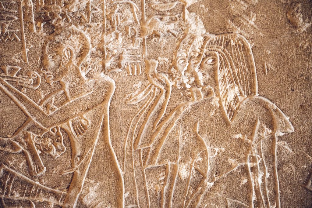An ancient Egyptian carving on a weathered stone surface depicting women and servants