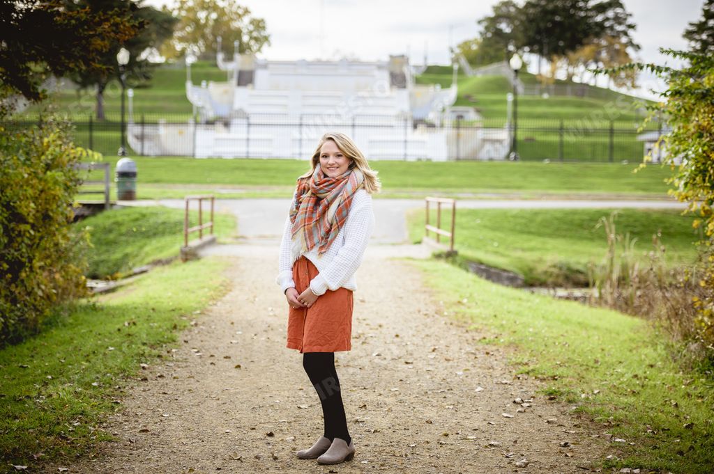 A shallow focus shot of a female standing on a pathway and smiling at the camera