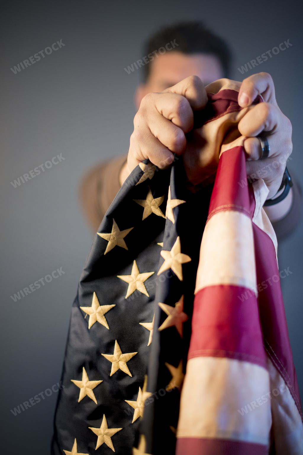 A vertical closeup shot of a person holding up the united states flag towards the camera