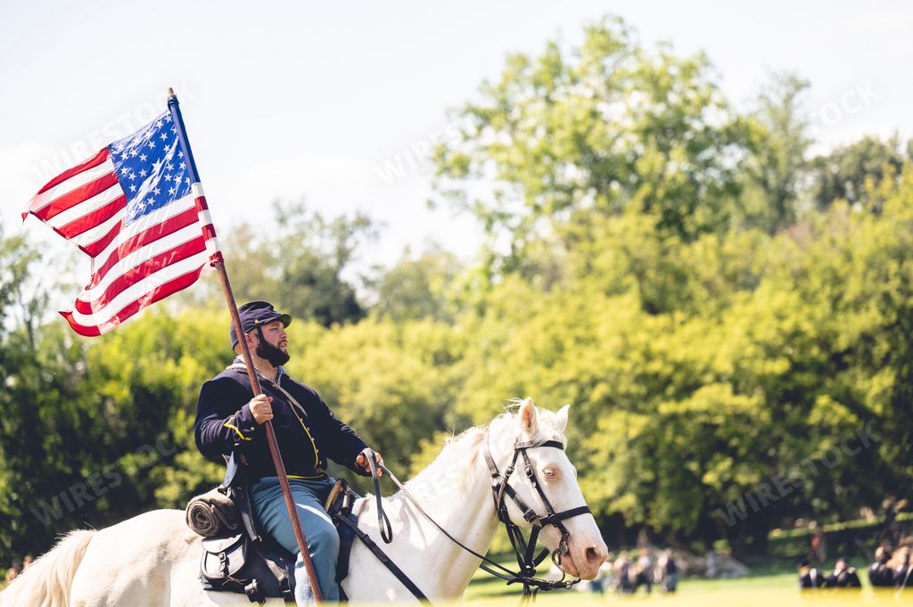 A soldier riding a horse and raises the flag of America during military performance in the Civil war reenactment in Jackson city, Michigan, USA
