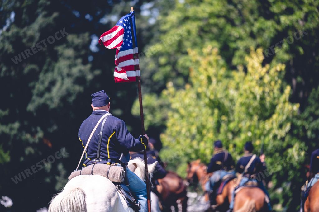A soldier riding a horse and raises the flag of America during military performance in the Civil war reenactment in Jackson city, Michigan, USA