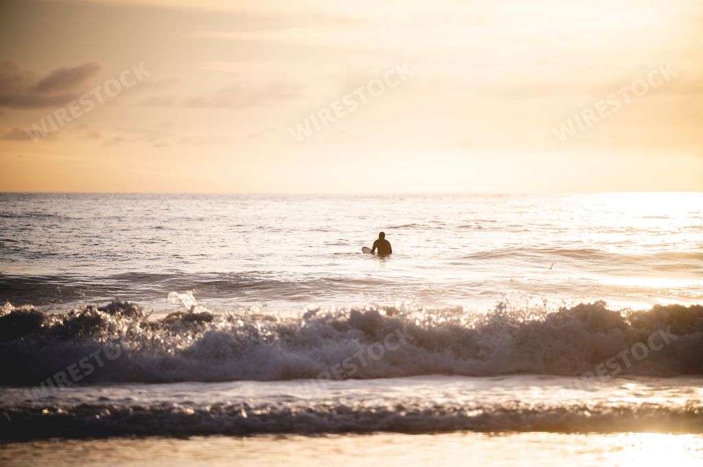 A Surfer hitting the waves at Newport Beach in California, USA at sunset