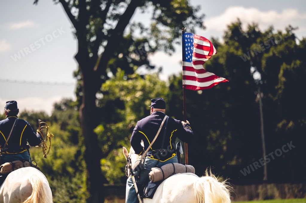 A confederate reenactor riding a horse with a flag of the United States at the Civil War reenactment