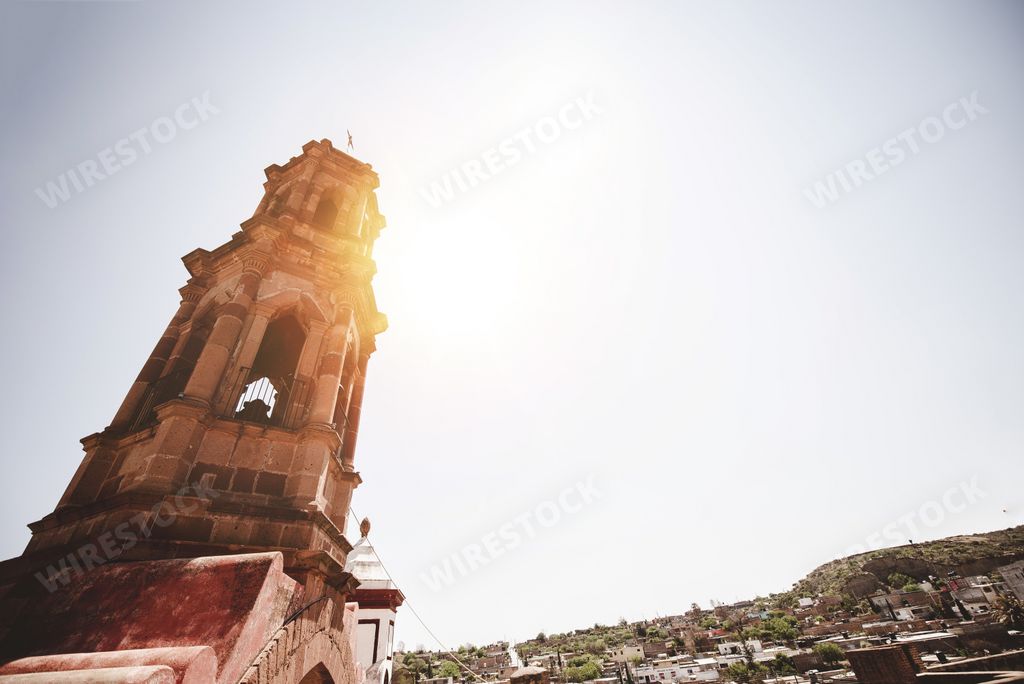 A low angle shot of a church bell tower with a bright sky in the background in Zacatecas Mexico