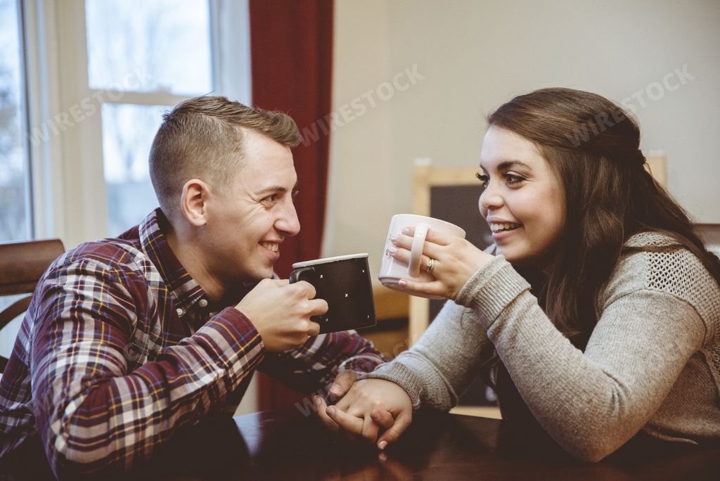 A couple holding hands and drinking coffee under the lights with a blurry background