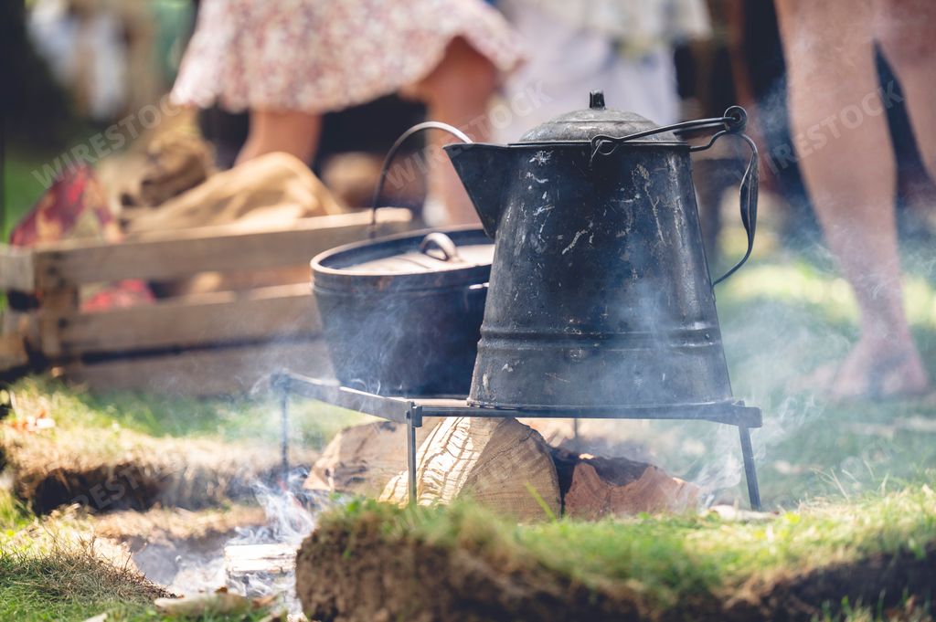 The old metal cooking pots on smoking wooden logs during the American Civil War reenactment event.