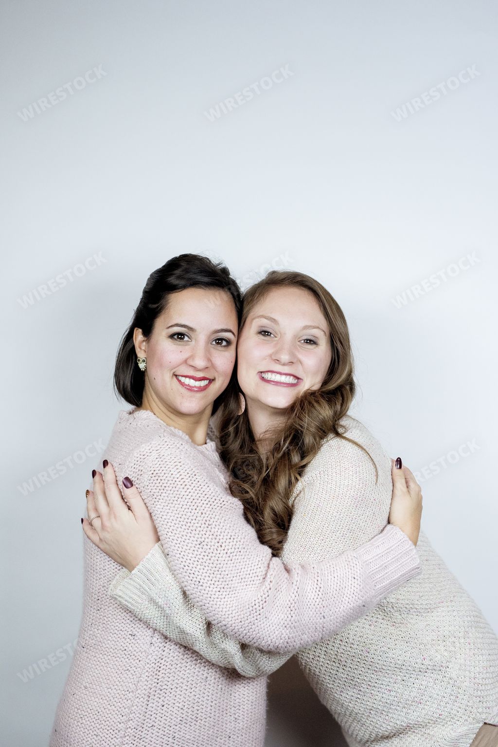 A vertical shot of friends hugging each other and smiling towards the camera