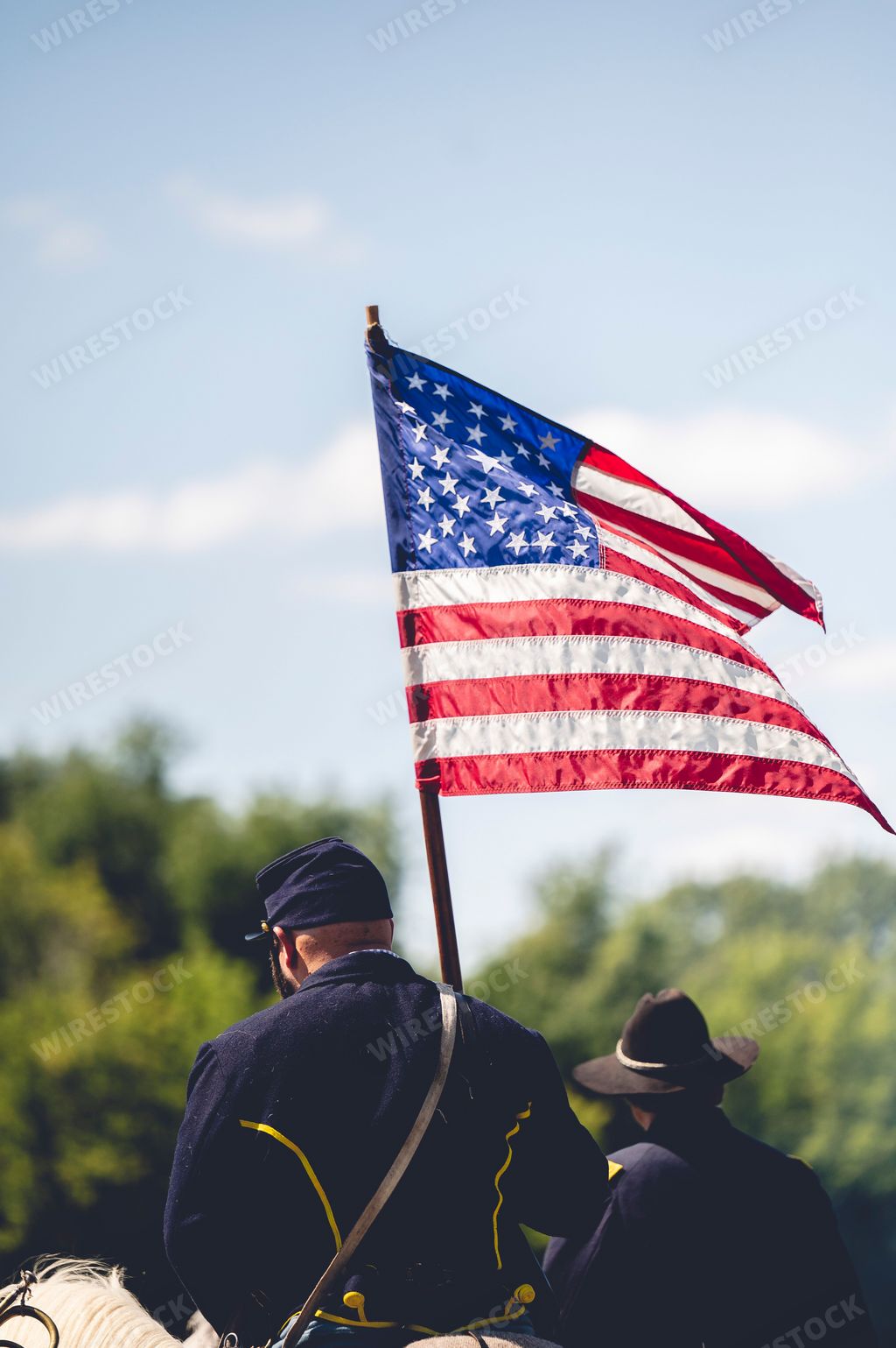 A vertical shot of a soldier holding the flag of America during military performance in the Civil war reenactment in Jackson city, Michigan, USA