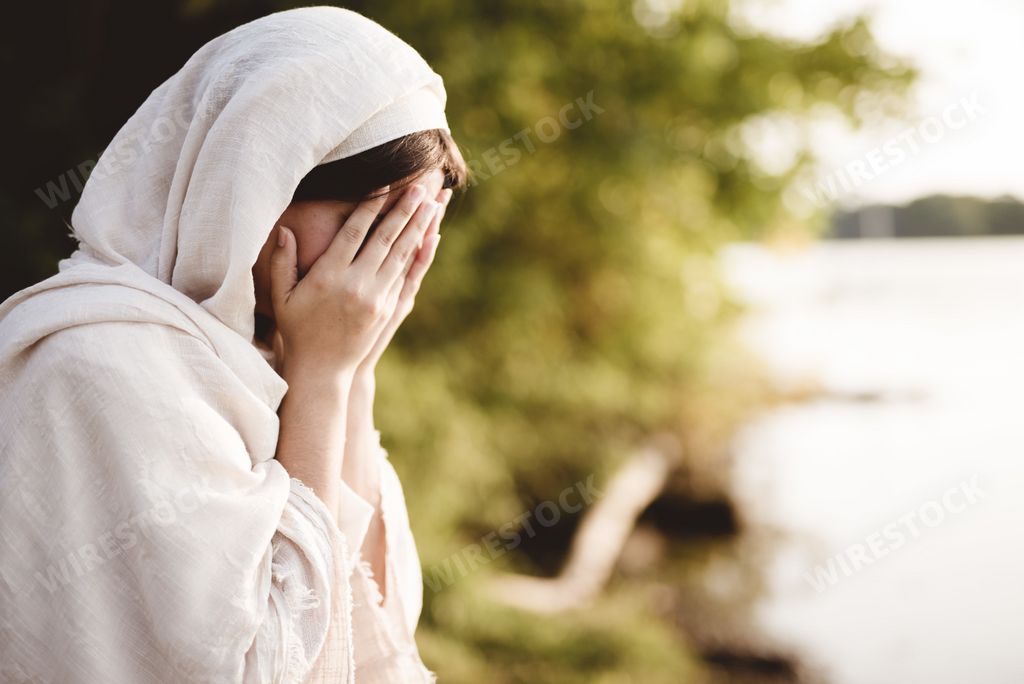 A closeup shot of a female wearing a biblical robe praying - concept confections of sin