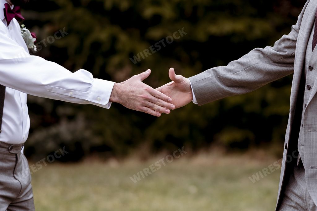 A closeup shot of a groom and his best man shaking hands