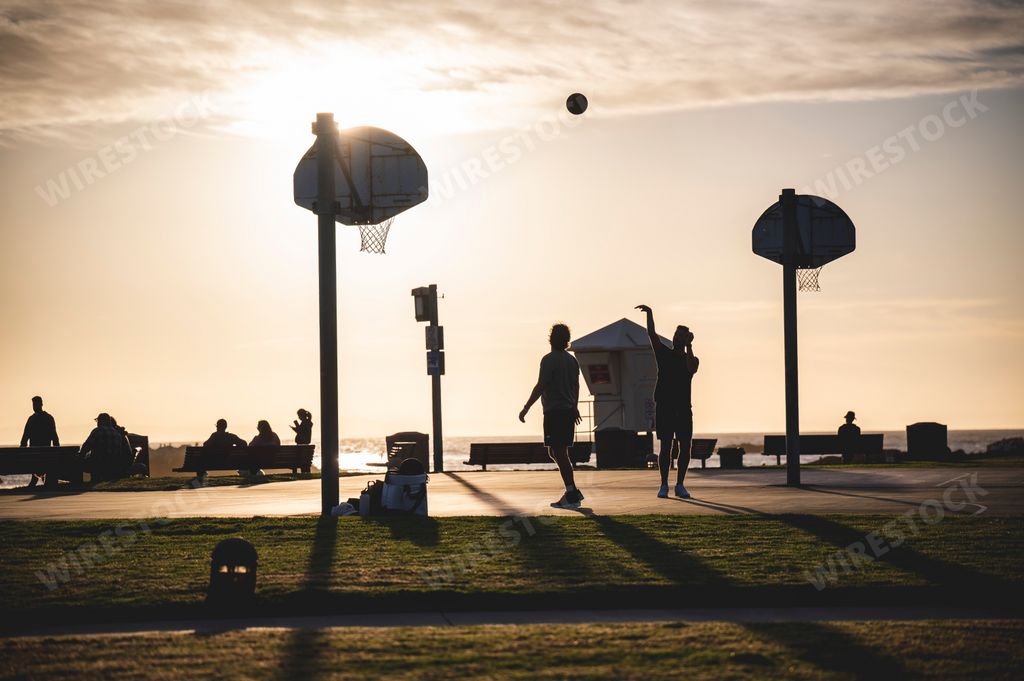People shooting a basketball as a silhouette at Laguna Beach California during sunset