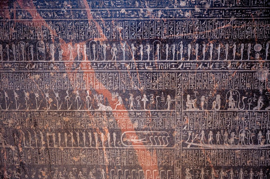 A black stone wall with Egyptian hieroglyphs and deities depicted on it in the Egyptian Museum in Cairo