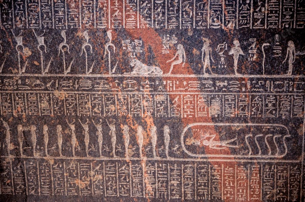 A background of Egyptian hieroglyphs and depictions of gods on a black stone surface in the Egyptian Museum in Cairo