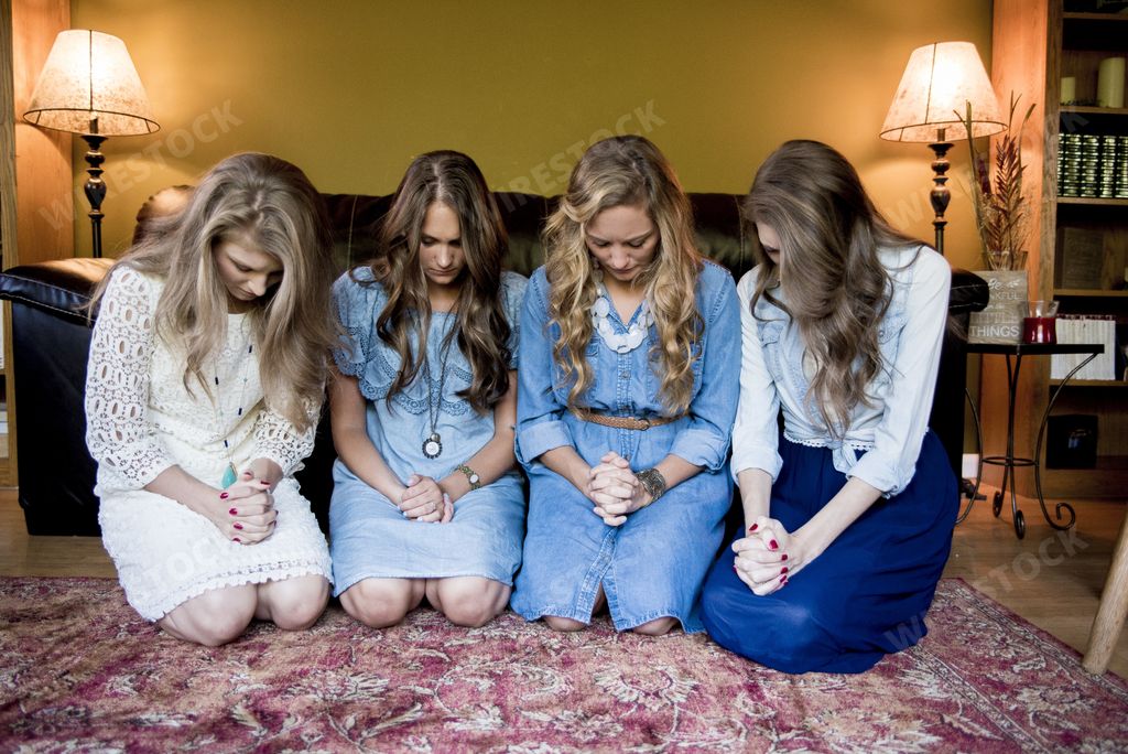 Four young girls next to each other looking down in a room