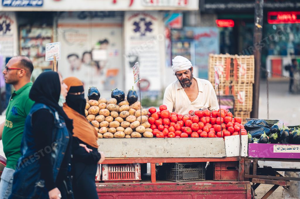 A bearded Egyptian man selling vegetables at a busy market in Cairo, Egypt
