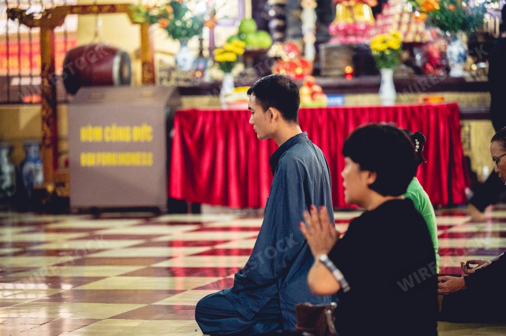 The Buddhist worshipers kneeling and praying at the altars of Buddhist idols in Hanoi City, Vietnam