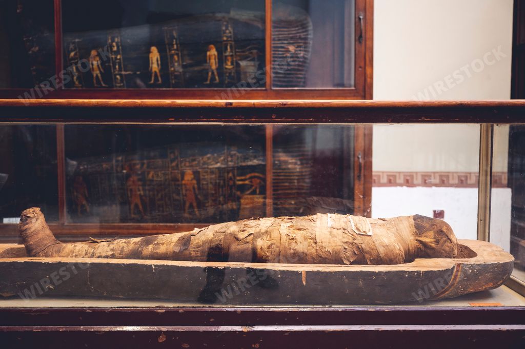 A mummified body wrapped in aged linen with an open lid in the Egyptian Museum in Cairo