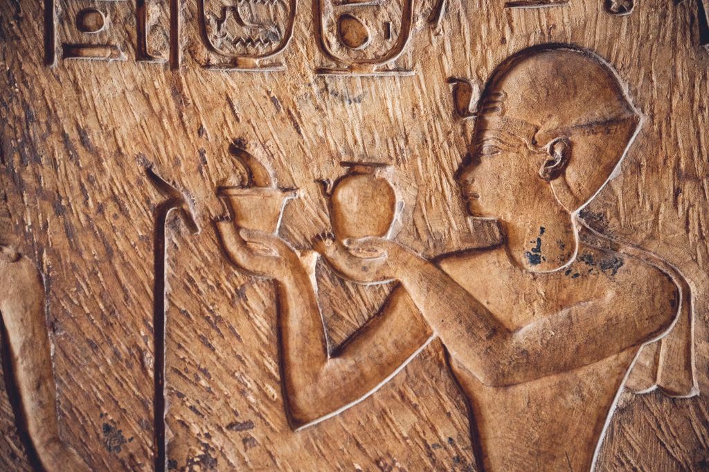 A closeup of a depiction of a pharaoh making offerings to Osiris on a stone surface in the Egyptian Museum in Cairo