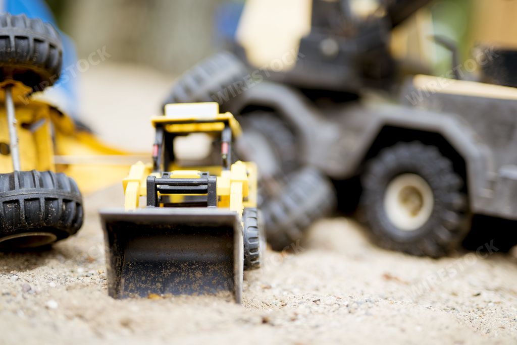 A closeup shot of a yellow bulldozer on a sandy surface with a blurred background