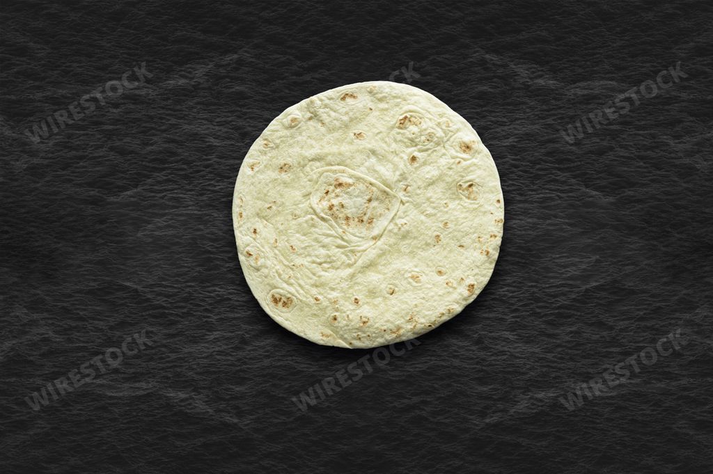 An overhead shot of a tortilla bread on a black surface