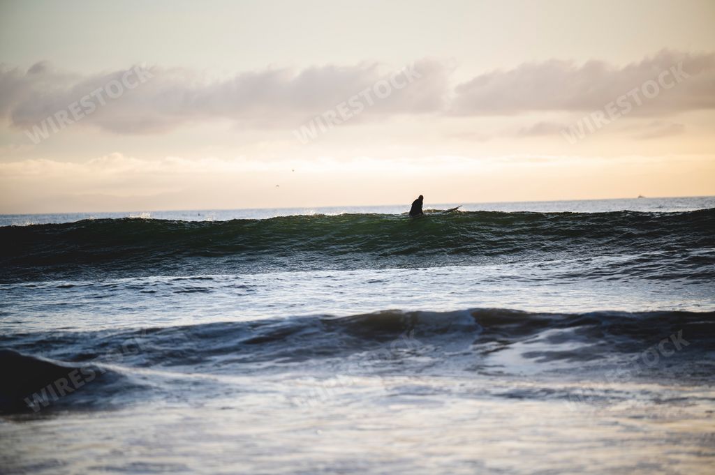 A Surfer hitting the waves at Newport Beach in California, USA at sunset