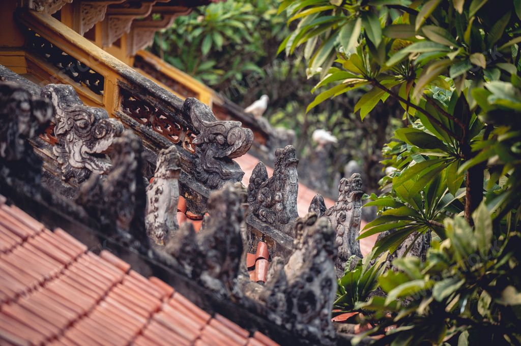 An outdoor view of the old tile roof and animal figures of a Buddhist temple in Vietnam