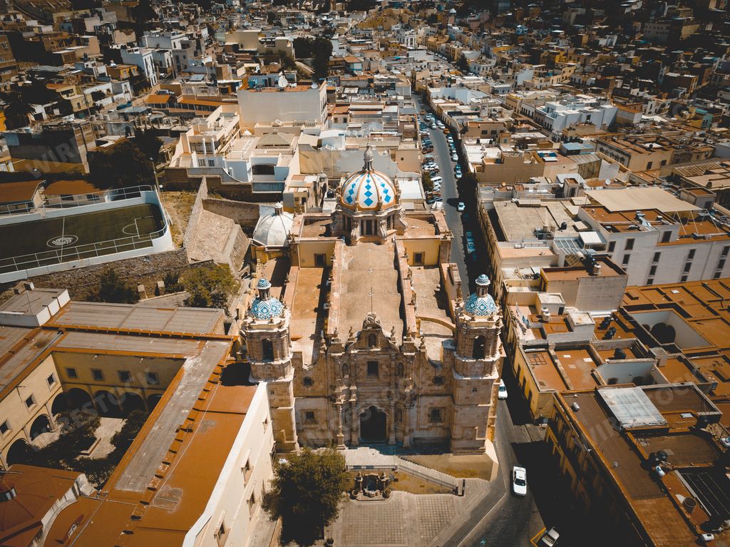An aerial shot of a big cathedral in the middle of buildings Zacatecas Mexico