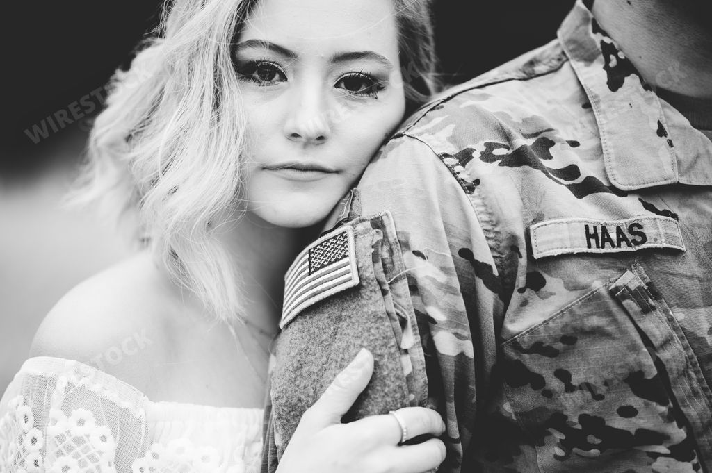 A dramatic grayscale shot of an attractive female holding an American soldier's arm
