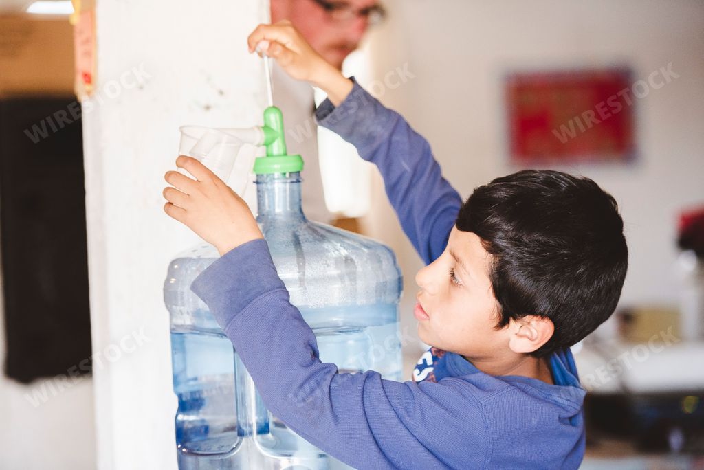 A young Mexican boy pumping some water out of a jug