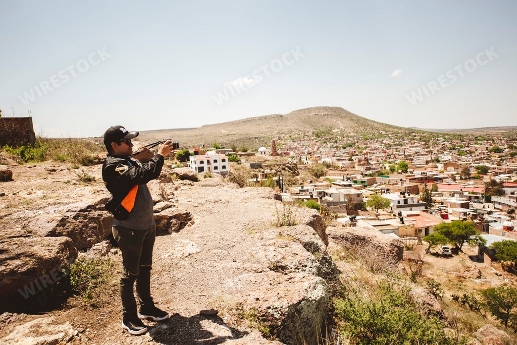 A male photographer on a mountain cliff taking aerial shots of Zacatecas, Mexico
