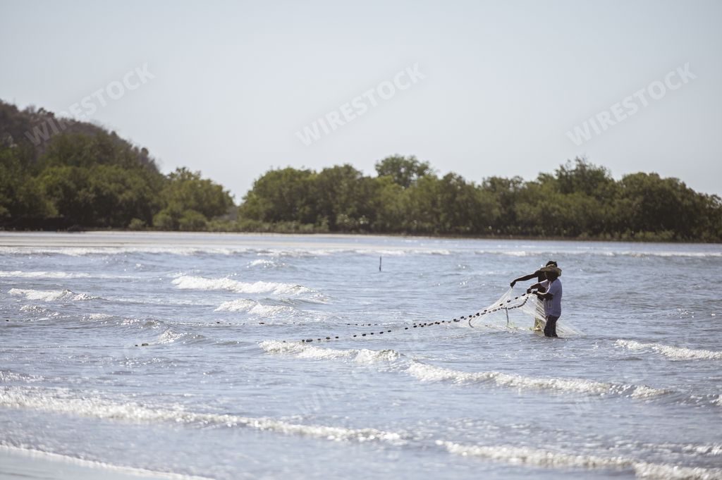 Man fishing with a net in the Philippines ocean. Waves and wind blowing.