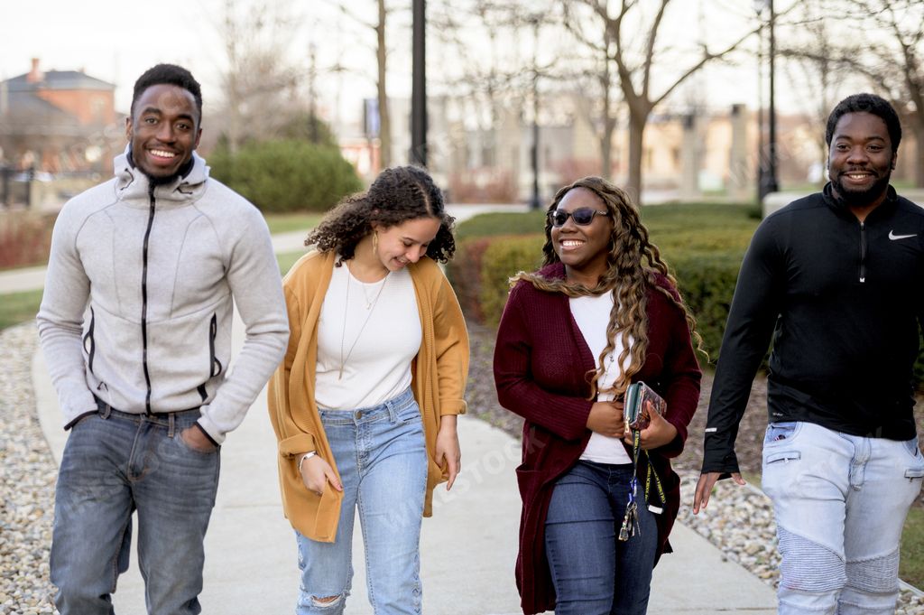 A group of people walking through a park under sunlight with a blurry background