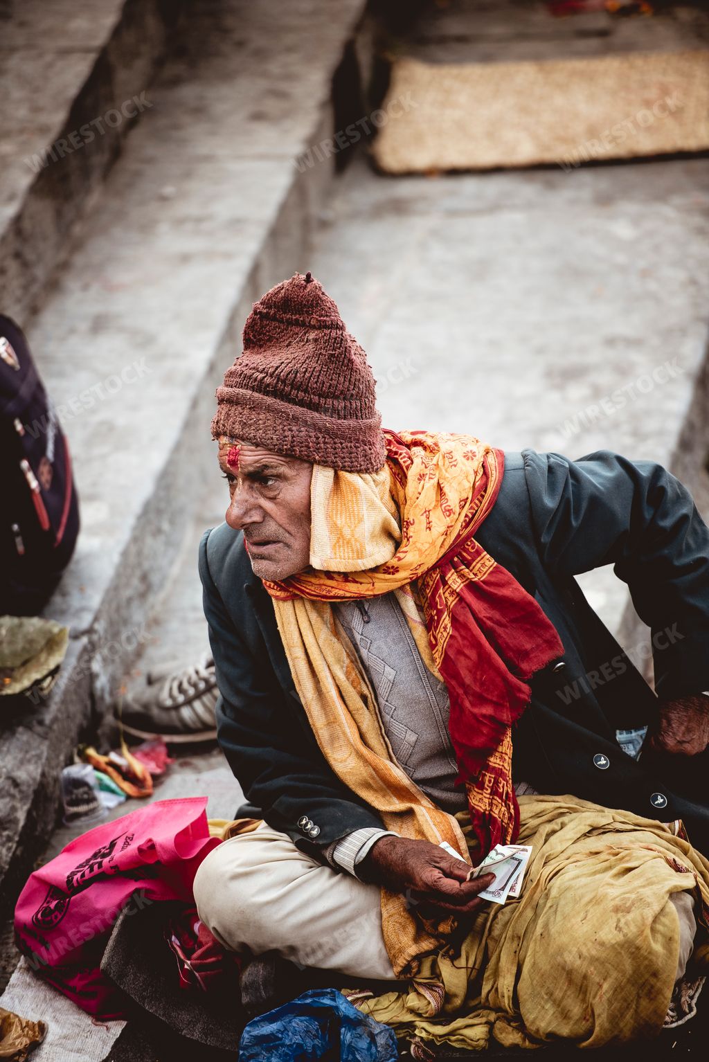 A closeup shot  of an old man with traditional Hindu clothes sitting on the street