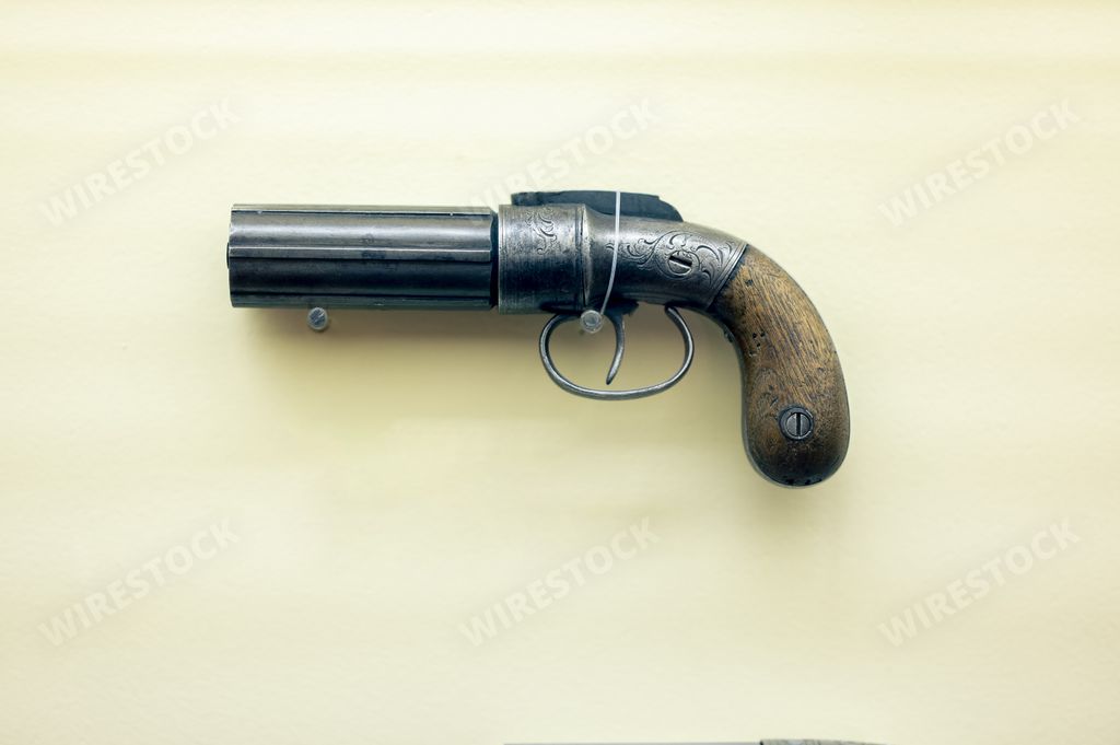 An old vintage pepper-box revolver isolated on a light yellow background
