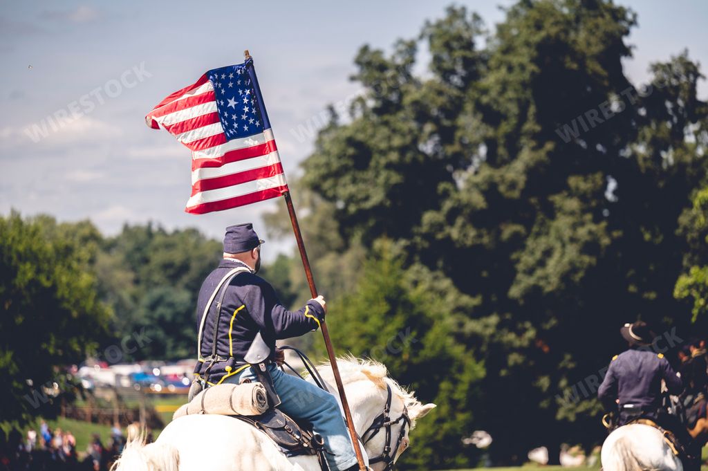 A soldier riding a horse and raises the flag of America during military performance in the Civil war reenactment in Jackson city, Michigan, USA