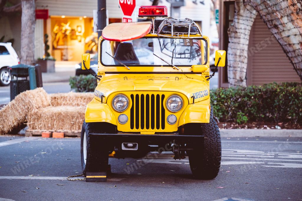 A Lifeguard yellow Jeep with a surfboard on top at Laguna Beach, California