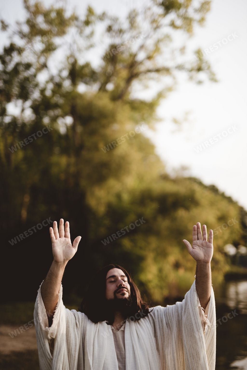 The Jesus Christ whit his hands up towards the sky while his eyes are closed