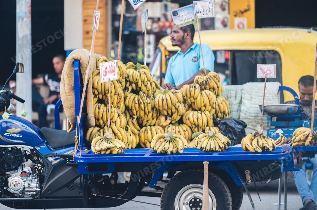 A bearded Egyptian man selling bananas at a busy market in Cairo, Egypt