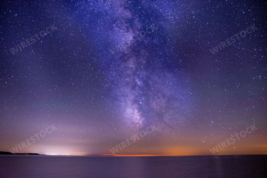 A breathtaking shot of the sea under a dark and purple sky filled with stars