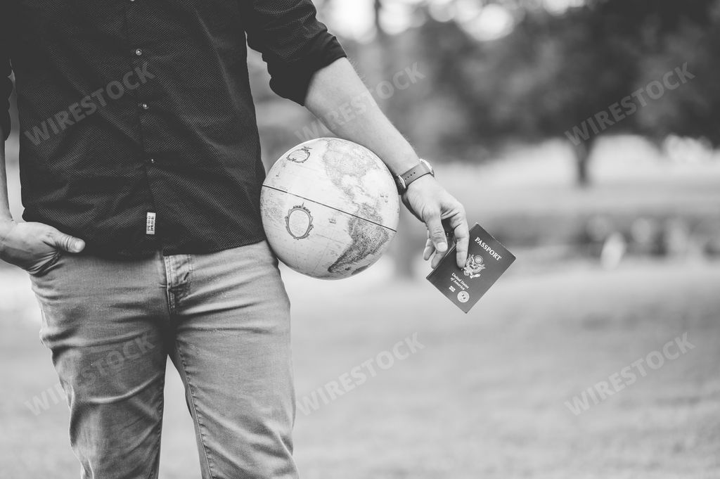 A Caucasian male holding a globe figure and his passpor