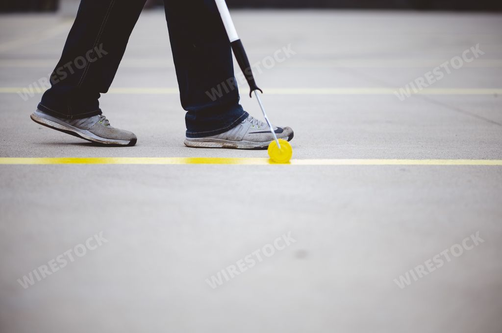 A view of a person repainting the parking lines of the asphalt of a parking lot with yellow paint