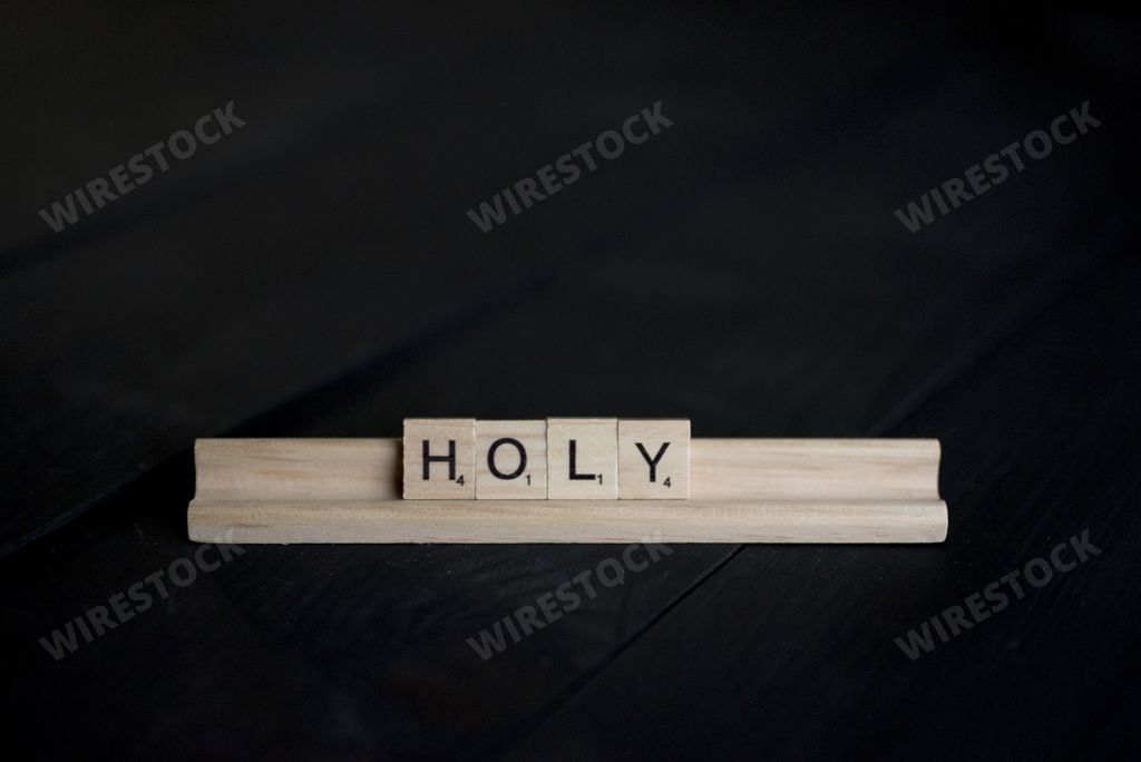 A closeup shot of wooden blocks spelling holy with a black background