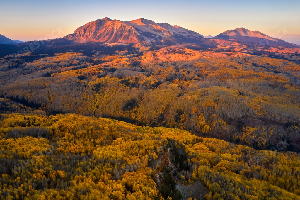An aerial landscape view of two distant mountain ranges with a foreground of lush green trees