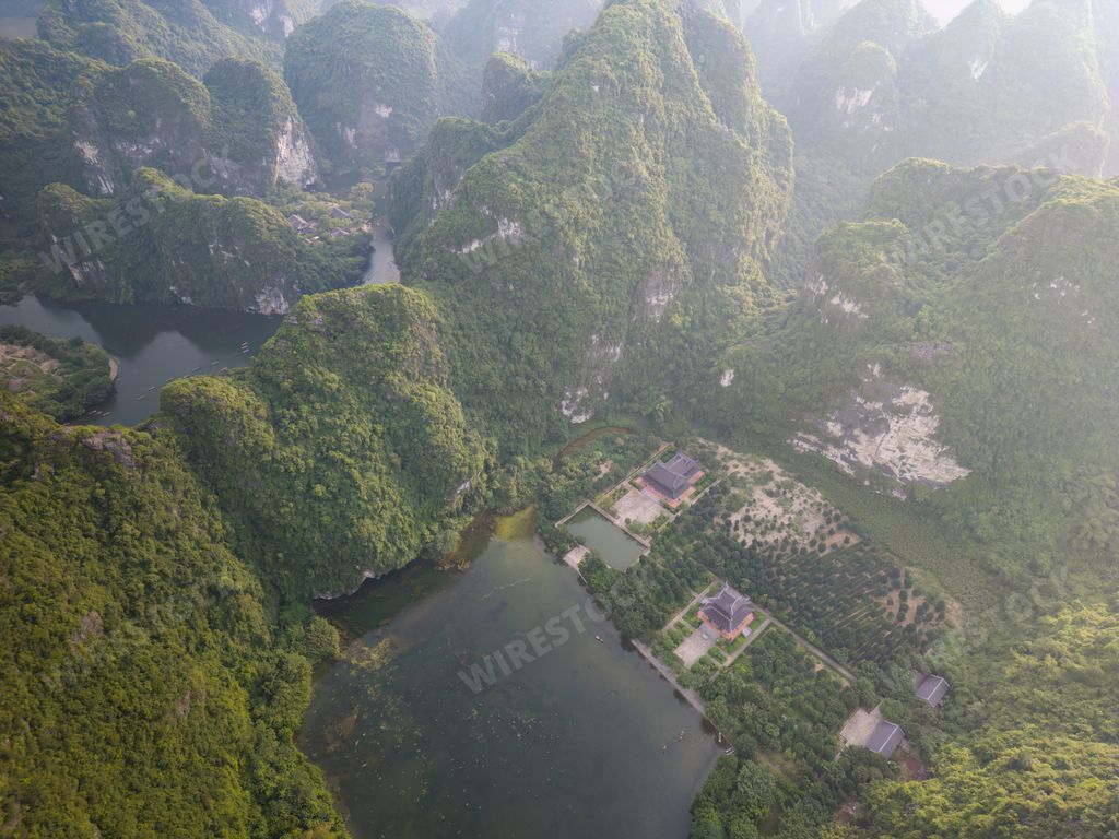 Aerial view of a serene landscape with lush green mountains and a calm river in Ninh Binh, Vietnam