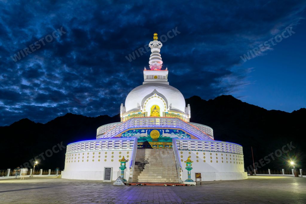 The beautiful Shanti Stupa at nighttime under a cloudy dark sky, India
