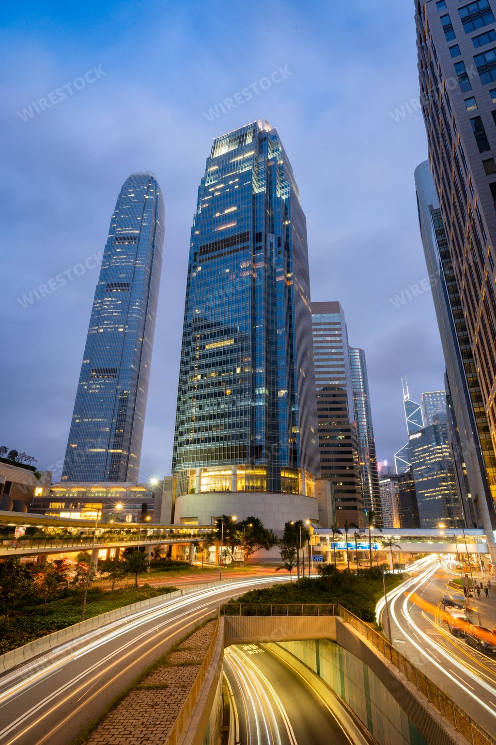 An evening street scene in Hong Kong with skyscrapers and light trails on the roads