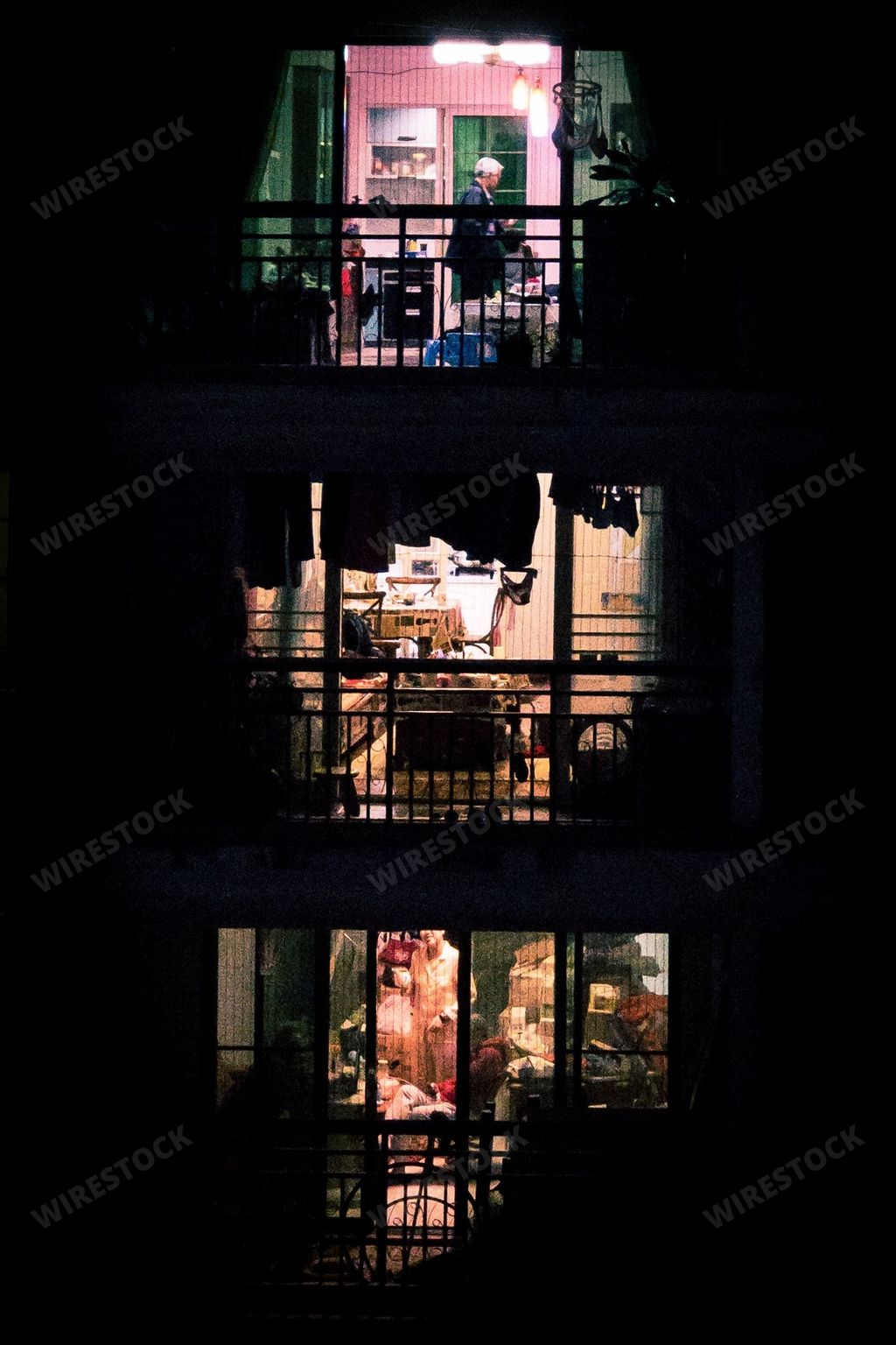 A night view of an apartment building with blinking lights in windows and people moving inside