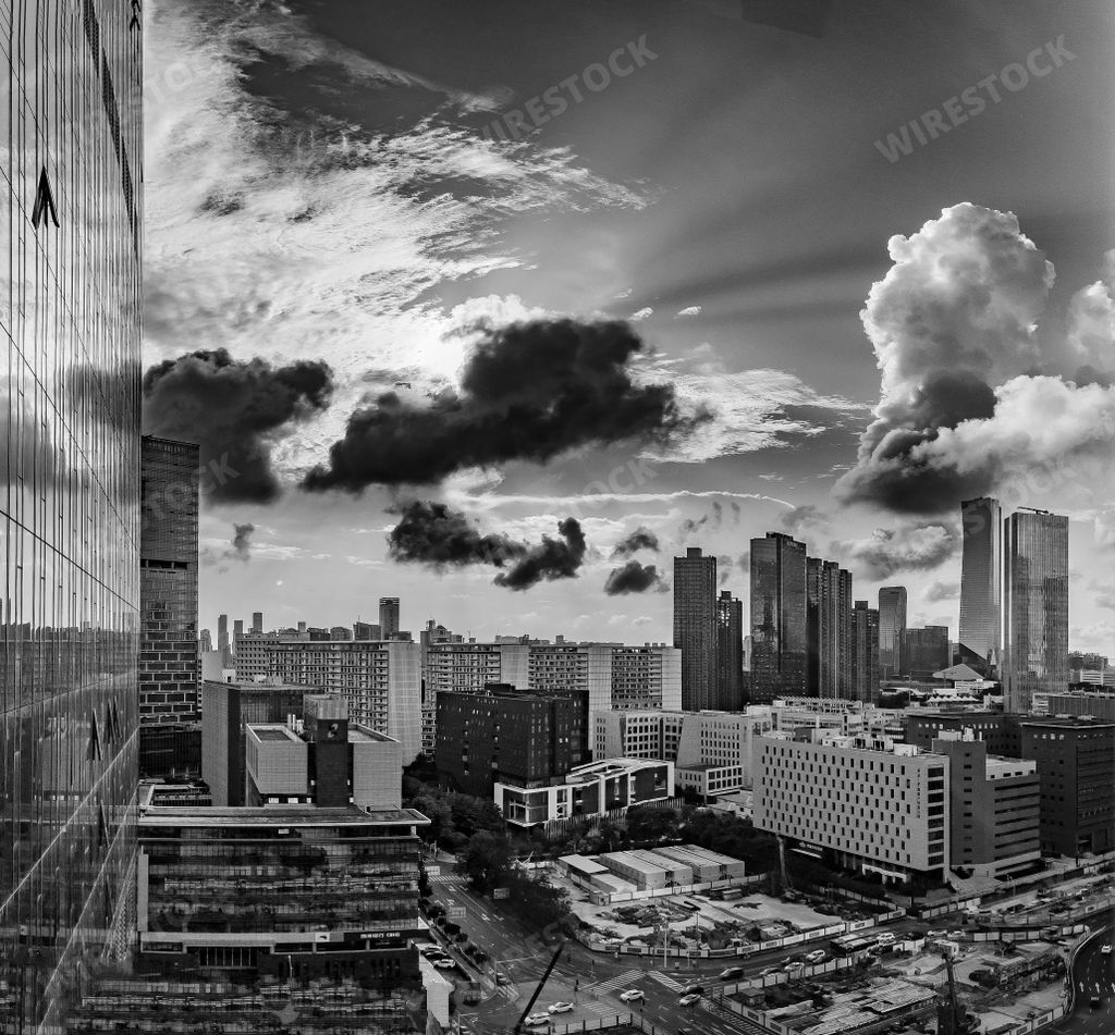A grayscale shot of a modern city skyline under dark cloudy sky
